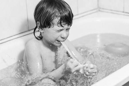Happy handsome child boy bathes in a bathroom with balloons. Concept of happiness and family.