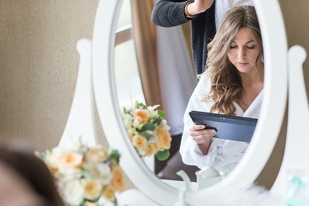 Young beautiful bride applying wedding makeup by professional makeup artistの写真素材