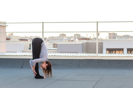 Young woman doing yoga and doing exercises on the mat on the roof.の写真素材