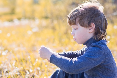 A child sits and thinks. Boy dreaming on grass and sad.の写真素材