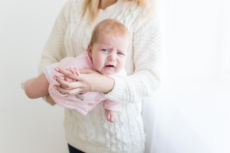 Young beautiful mother comforts, so as not to cry her infant daughter. motherhood concept, love and care.の写真素材