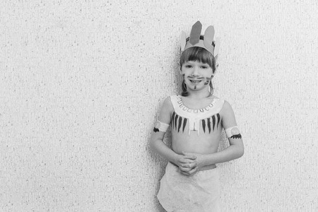 Blond boy playing injun. Child painted face paint and wearing a mask redskin.