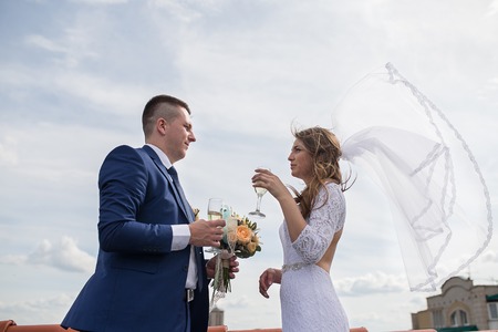 happy gorgeous bride and stylish groom with true emotions on the roof on background of view of city buildingsの写真素材