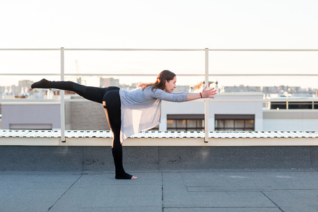 Young woman doing yoga and doing exercises on the mat on the roof.の写真素材