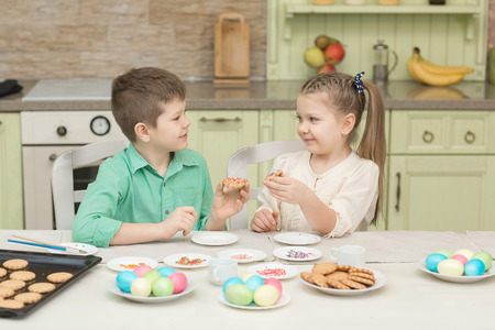 Cute kids baked cookies and tasting it at the table in the home kitchenの写真素材
