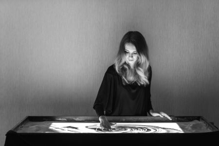 The woman draws on sand, sand animation, sand is pouring from his hands