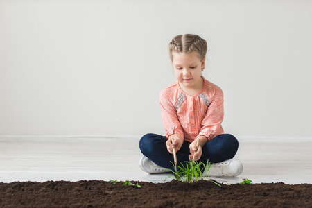 The girl fumbles with the land and plants a plantの写真素材