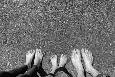 Feet family in the sea on the sandy beach. Vacation conceptの写真素材