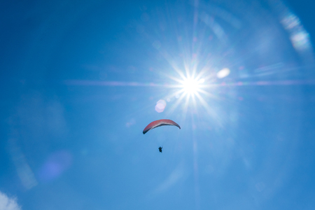 Paraglider flying against the blue sky with white clouds.の写真素材