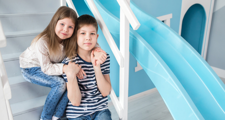 Portrait of happy children which are sitting on the stairs in the houseの写真素材