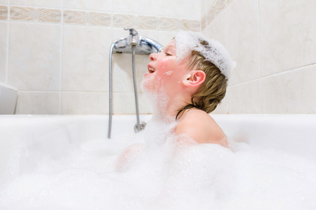 little child is washing her hair in bathの写真素材