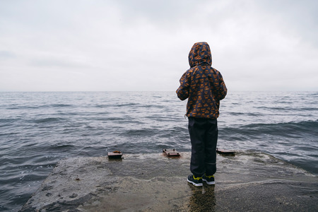 Little boy looking at the sea at winter from pier.の写真素材