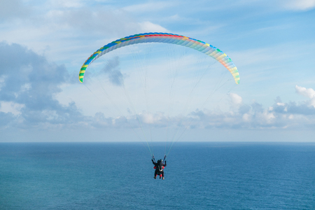 Flying a tandem paraglider over the sea with views of the horizonの写真素材