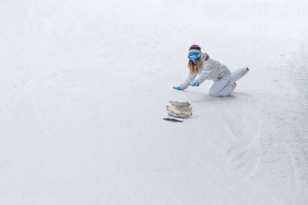 Young girl snowboarder snowboarding released from the hands down the mountainの写真素材