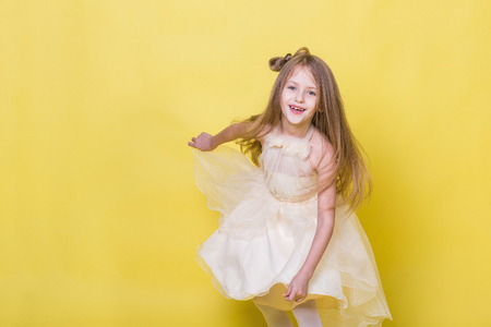Teenager girl in a dress on a yellow background poses for the cameraの写真素材