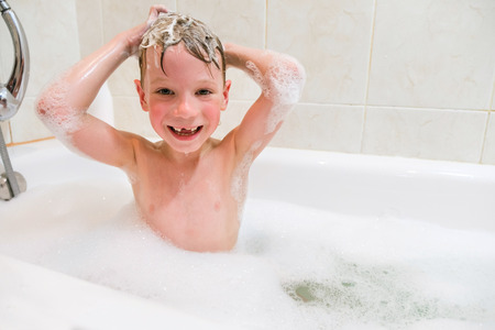 little child is washing her hair in bath