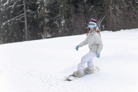 Young woman snowboarder in motion on snowboard in mountainsの写真素材