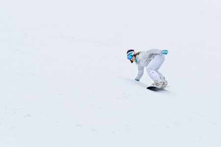 Young woman snowboarder in motion on snowboard in mountainsの写真素材
