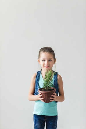 Girl standing on a white background with a plant on Earth Dayの写真素材