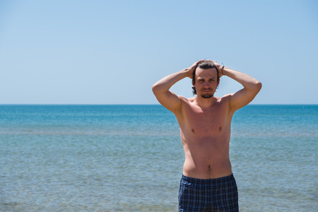 Handsome man posing on beach, portrait. Hand in hair.の写真素材