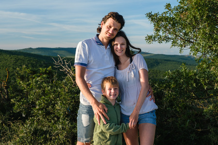 Family portrait mother, father and son on a background of mountains in summer wearing light clothingの写真素材