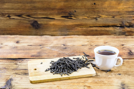 Fermented Ivan-tea on wooden board. Dry herbal natural tea. White cup with Ivan-tea. Side view.の写真素材
