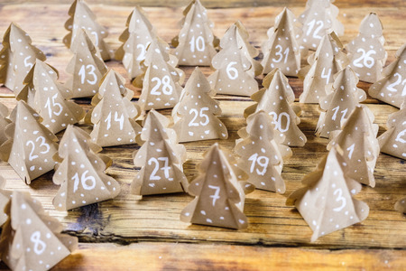 Handmade Christmas advent calendar Christmas trees Kraft paper with numbers in wood background.の写真素材