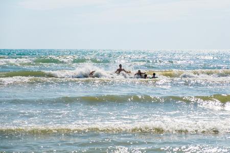 People with children in water wings swimming in the stormy sea in warm sunny day.の写真素材