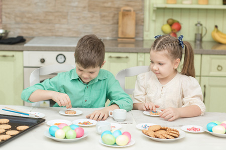 Cute children decorate cookies at a table in the home kitchenの写真素材