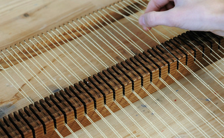 Weaving on a loom frame. Closeup womans hand puts the thread in the frame for weaving.