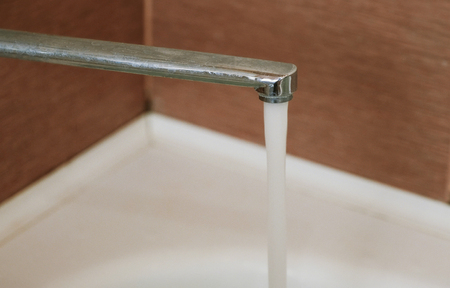 Faucet closeup. Water is poured from a chrome tap.