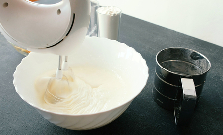 Close-up womans hands with a mixer whisk eggs with sugar in a bowl. Cooking apple pie.
