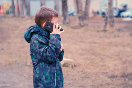 Boy speaks on a mobile phone in the Park.の写真素材