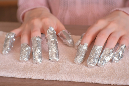 Removing gel Polish from nails. All fingers with foil on both hands. Close-up hand. Front view.の写真素材
