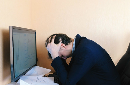 Tired man is working on computer compare graphics.