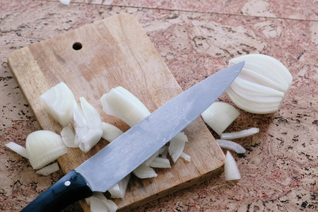 Knife and onion pieces on a wooden boardの写真素材