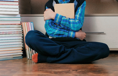 Unrecognizable seven-year-old boy sitting among books.