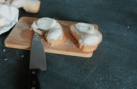 Closeup sandwiches with bread, butter and eggs on wooden board in black background. Making a sandwiches.の写真素材