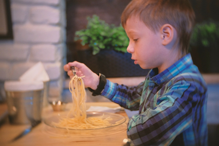 Boy eats spaghetti in the cafe.の写真素材