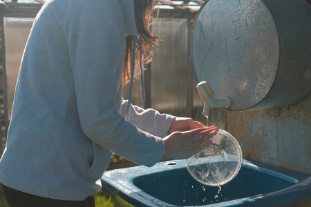 Woman washes a bowl in a rustic homemade sink. Hands close-upの写真素材