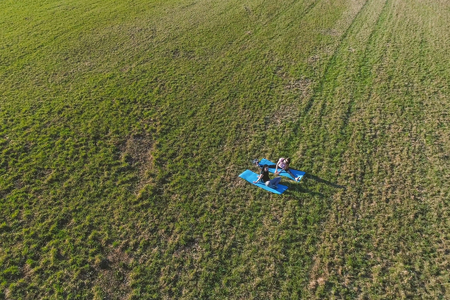 Two girls stretching on mats on the field. Aerial panoramic view.の写真素材
