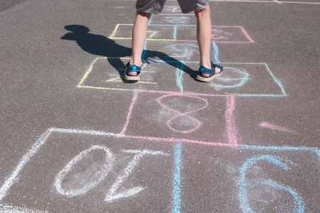 Boy jumps playing hopscotch in the street. Close-up legs.の写真素材
