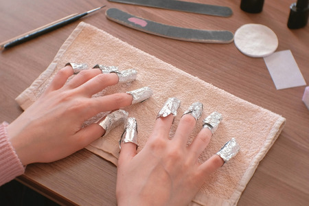 Removing gel Polish from nails. All fingers with foil on both hands. Close-up hand. Front view.の写真素材