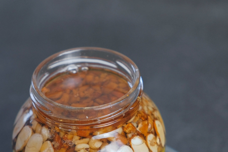 Rotating open jar with nuts in honey. Close-up top view.
