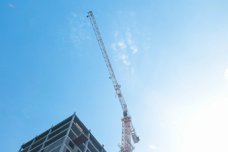 Multi-storey under construction building and construction crane on the background of clear sky.の写真素材