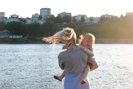 Mother and daughter on the river in the city. Mother with her daughter in her arms.の写真素材