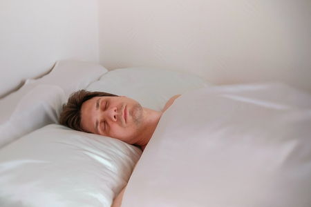 Man is sleeping in the bed alone.