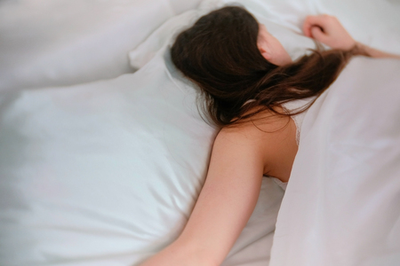 Young woman sleeping in bed. Flips over to the other side