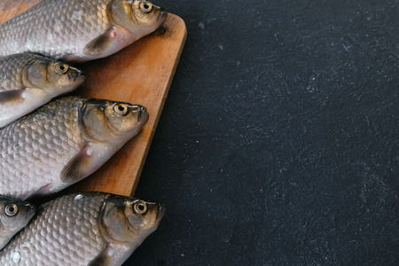 Cooking fish. Fresh small carps on the table on a wooden Board close-up.
