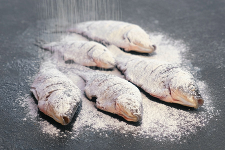 Carp fish in spices and flour on a black table.の写真素材